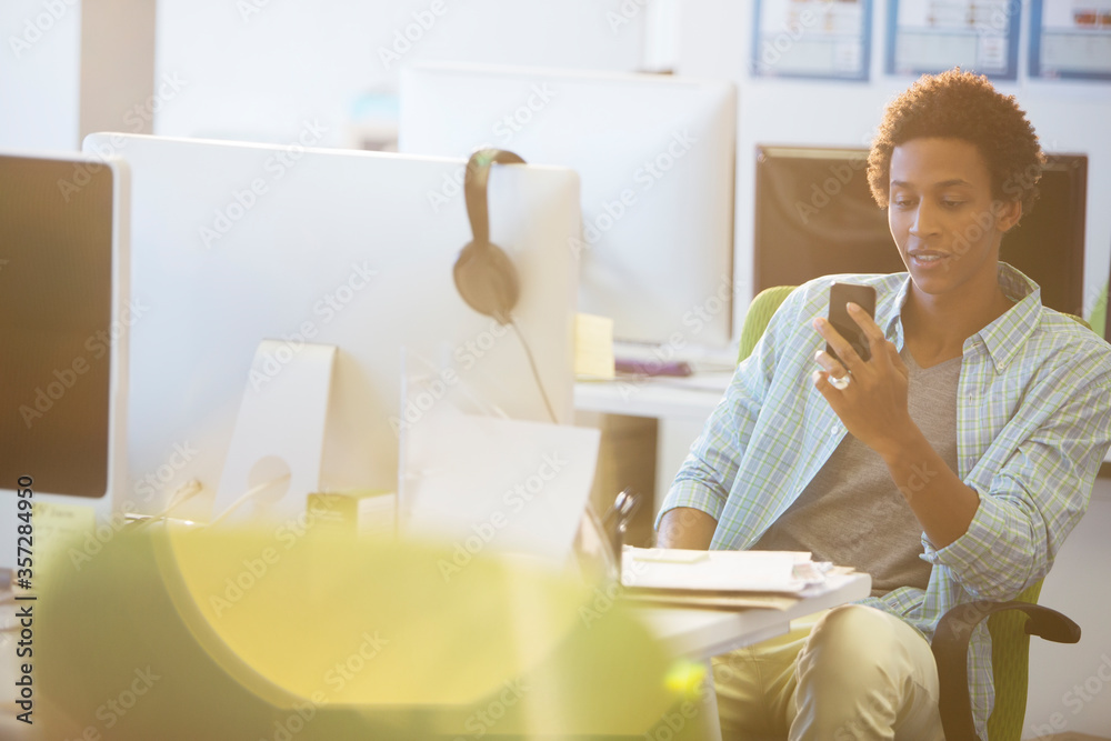 Businessman using cell phone at desk in office Businessman using cell phone at desk in office
