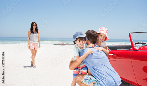 Father hugging daughter and son near convertible at beach © Dan Dalton/KOTO