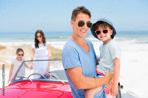 Father and son smiling near convertible on beach © Dan Dalton/KOTO