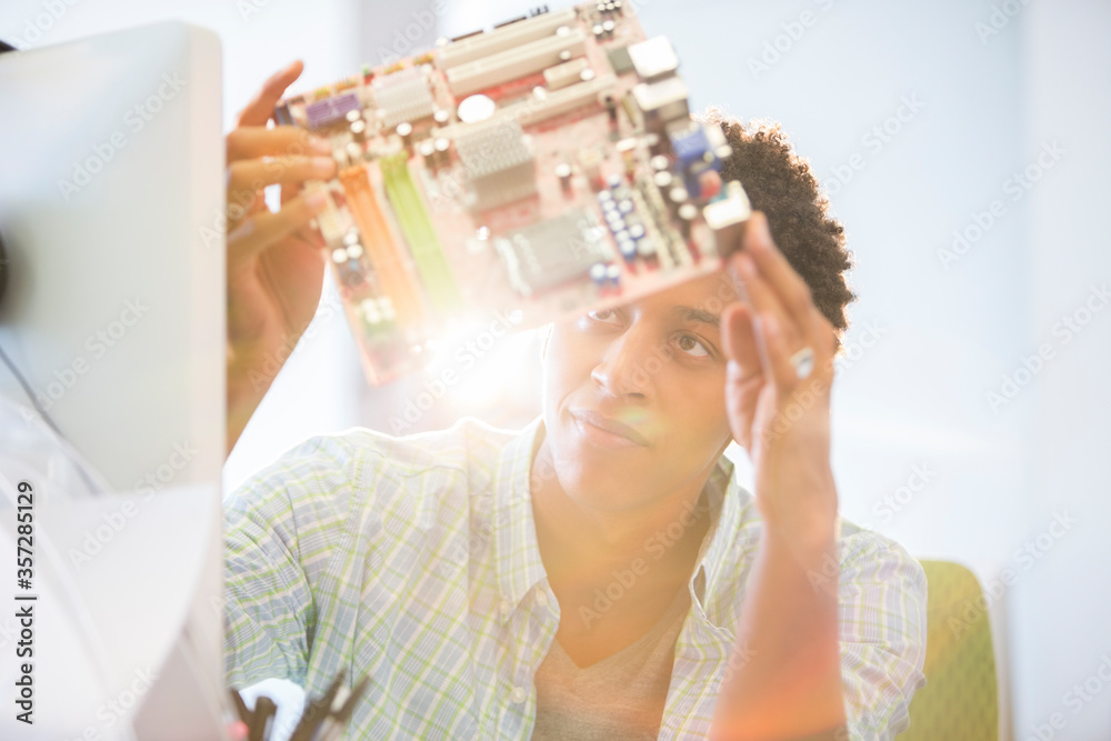 Fototapeta premium Businessman examining circuit board in office