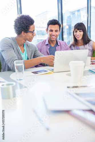 Business people sharing laptop in meeting © Robert Daly/KOTO