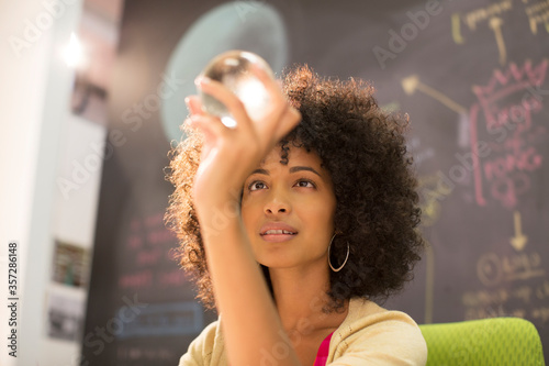 Businesswoman examining crystal ball in office photo