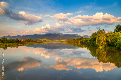 Bild auf Leinwand Mirroring of the mountainous landscape on the water surface of the dam at sunset