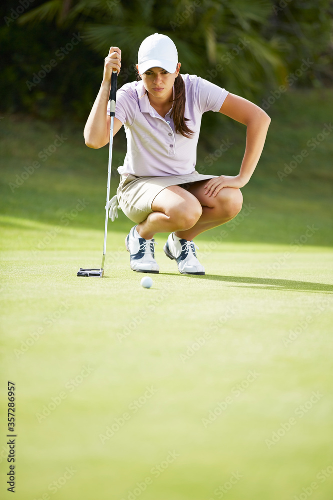 Woman preparing to putt on golf course