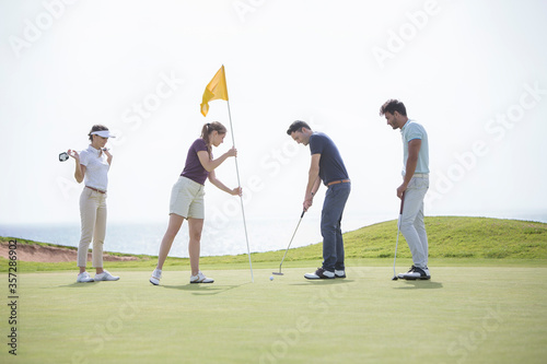 Friends putting on golf course