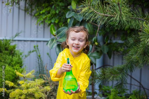 portrait of a happy girl helping to spray coniferous plants in a greenhouse