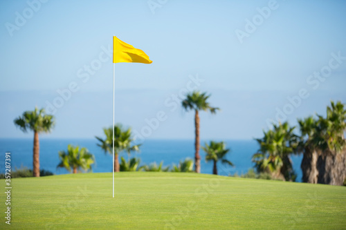 Flag in hole on golf course overlooking ocean photo