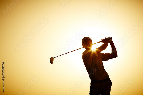 Silhouette of man swinging golf club photo