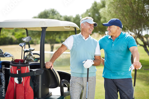 Senior men laughing next to golf cart