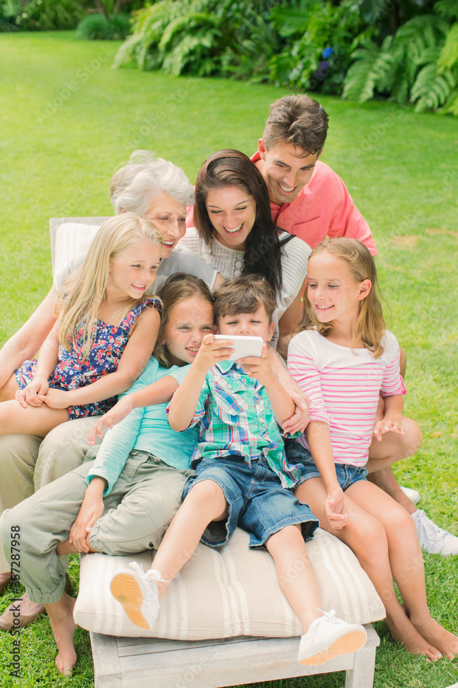 Family using cell phone together in backyard