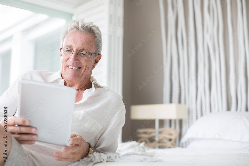 Older man using digital tablet on bed Older man using digital tablet on bed