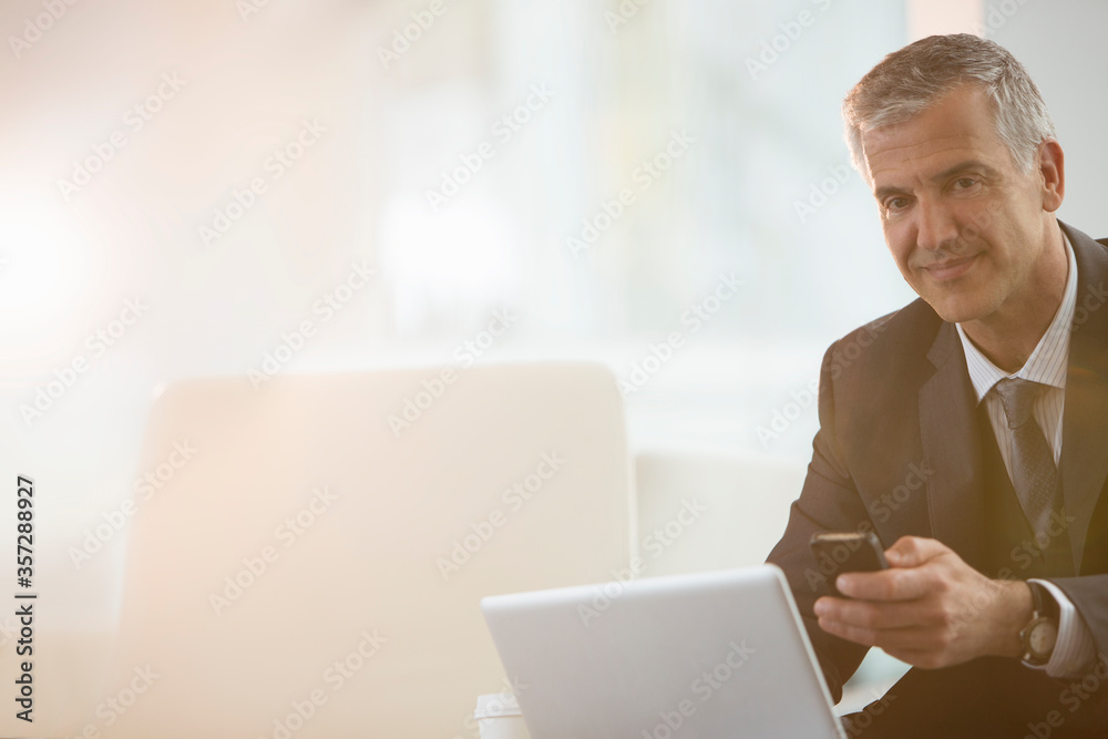 Businessman using cell phone and laptop in office Businessman using cell phone and laptop in office