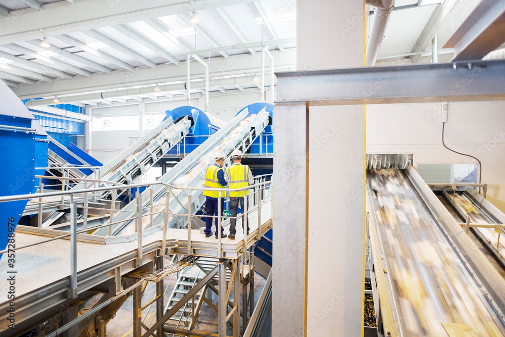 Workers talking on platform in recycling center