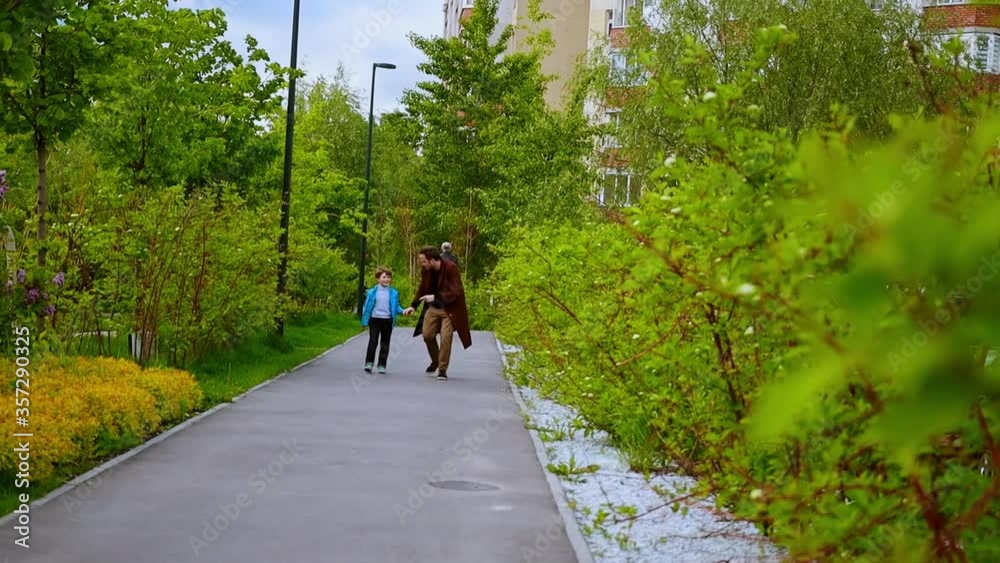 Young man and his little brother running in the park - happy family Young man and his little brother running in the park - happy family