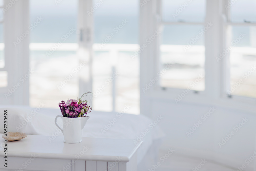 Vase of flowers on desk in bedroom overlooking ocean Vase of flowers on desk in bedroom overlooking ocean