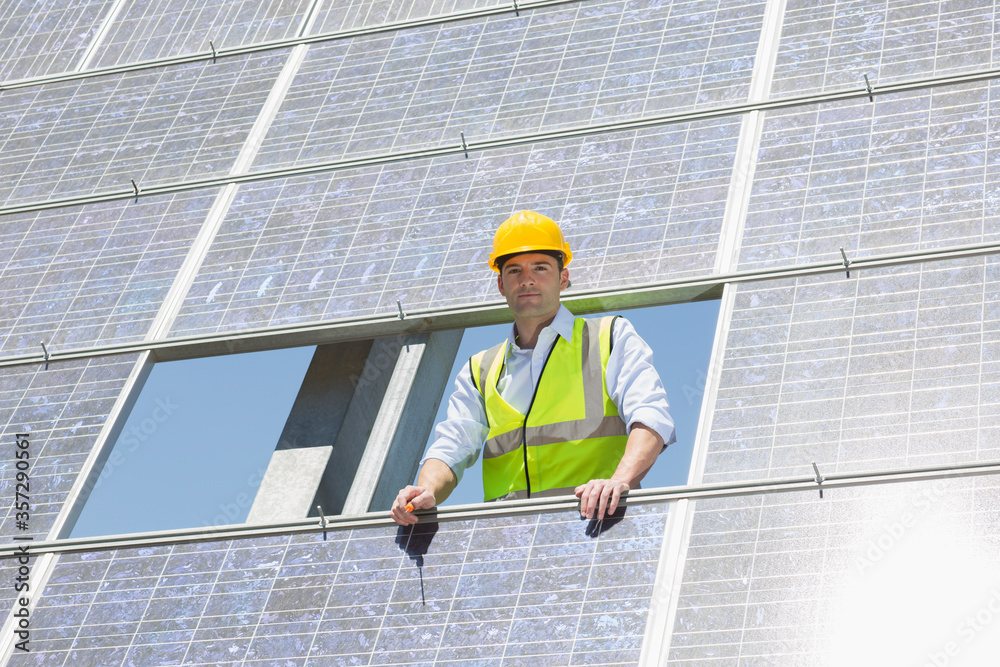 Worker examining solar panel in rural landscape Worker examining solar panel in rural landscape