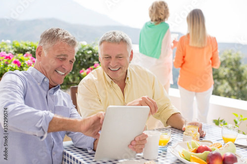 Senior men using digital tablet at patio table