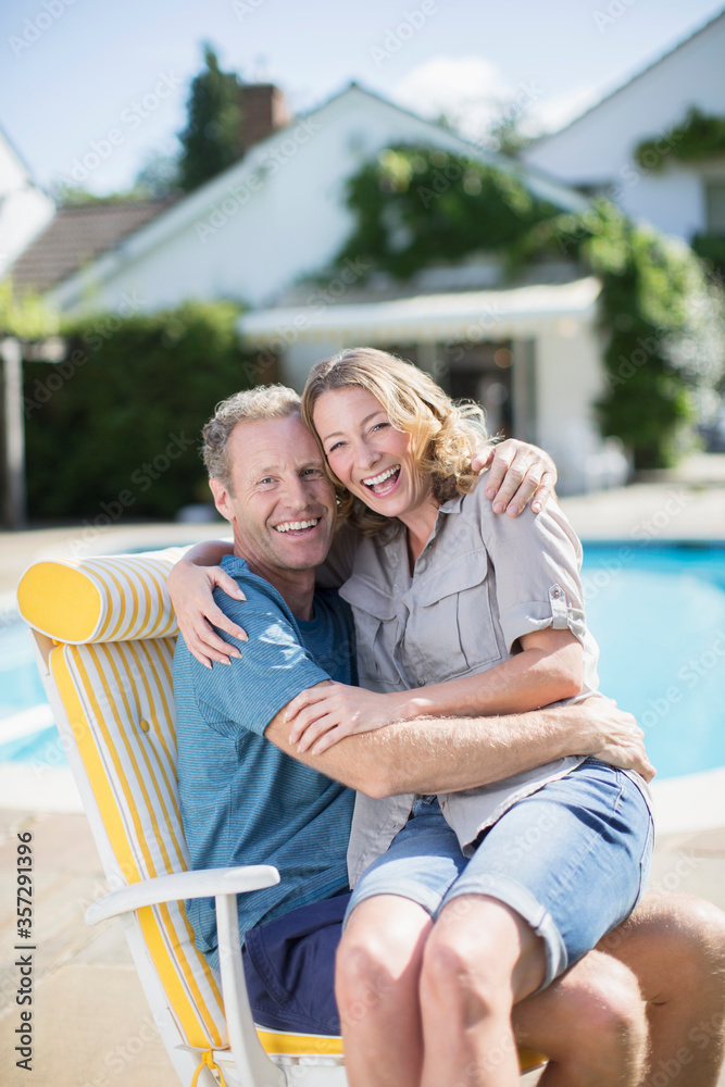 Fototapeta premium Couple sitting in lounge chair at poolside