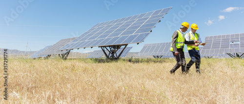 Workers walking by solar panels in rural landscape photo