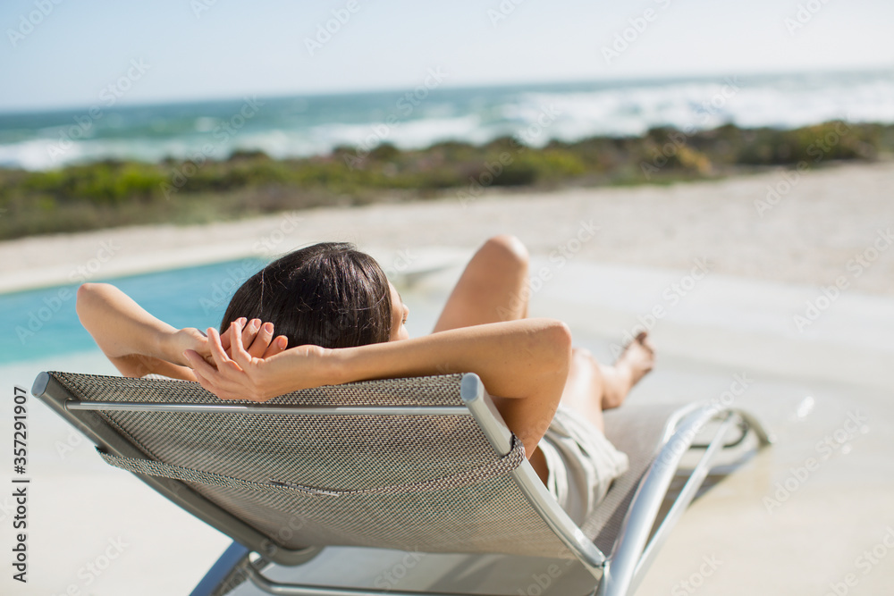 Woman sunbathing on lounge chair at poolside