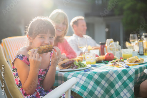 Φωτογραφία Girl eating corncob at table in backyard