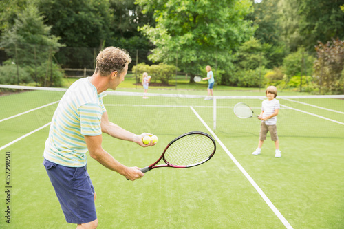 Family playing tennis on grass court © Robert Daly/KOTO