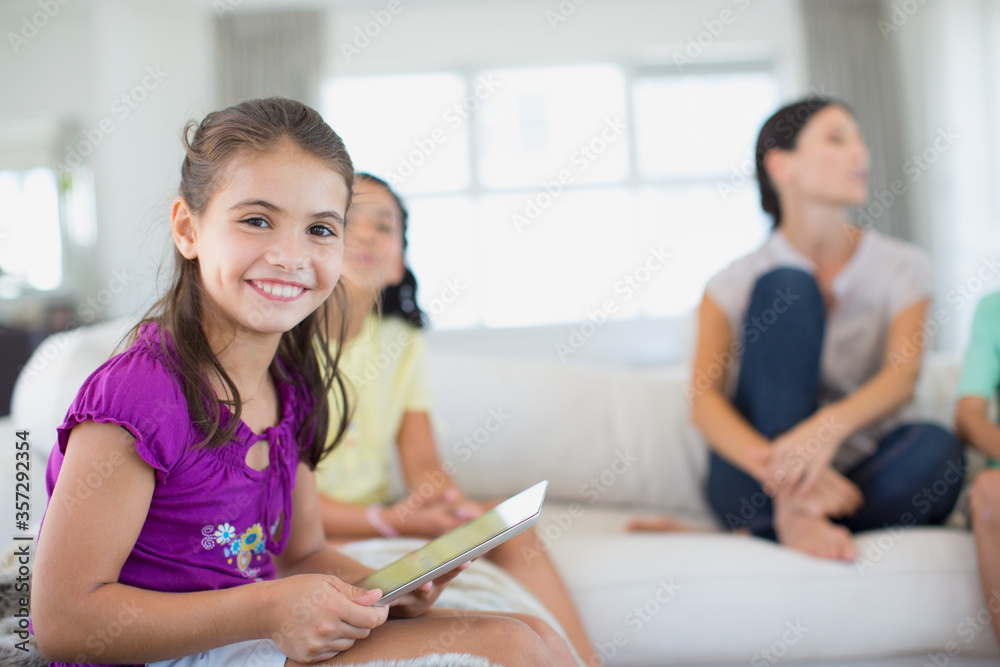 Fototapeta premium Girl using digital tablet on sofa in living room