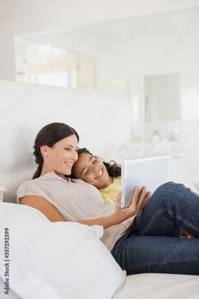 Mother and daughter using digital tablet on bed Mother and daughter using digital tablet on bed