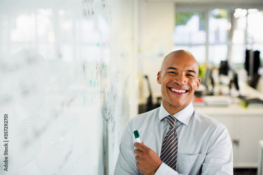 Businessman smiling at whiteboard in office