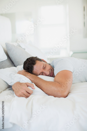 Man hugging pillow on bed