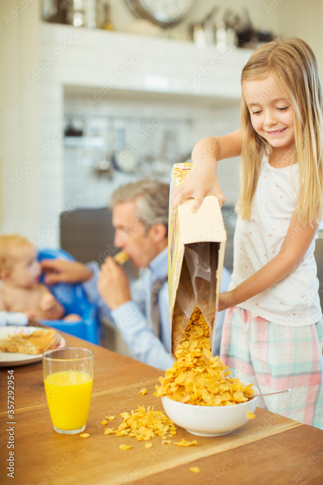 Girl pouring bowl cereal on breakfast table