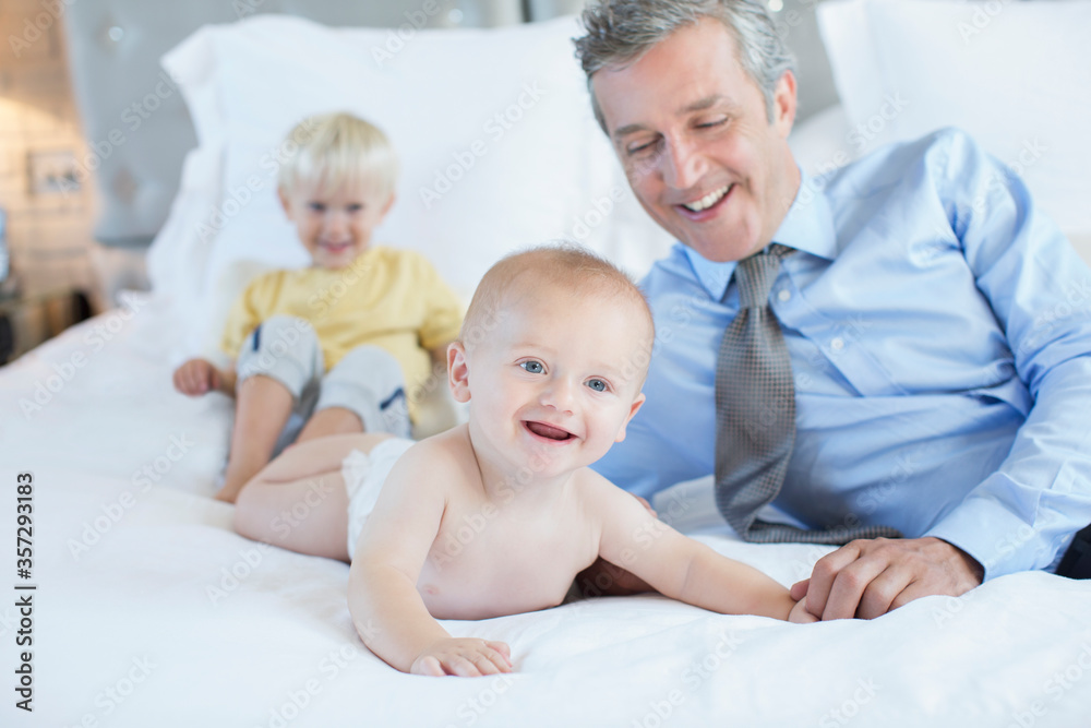 Father and children playing on bed