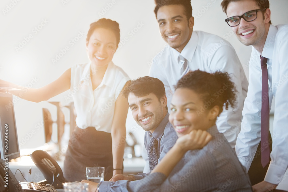 Business people smiling at computer in office Business people smiling at computer in office