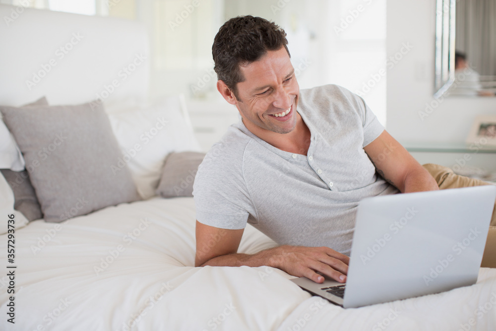 Man using laptop on bed