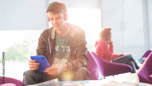 University student listening to headphones in lounge