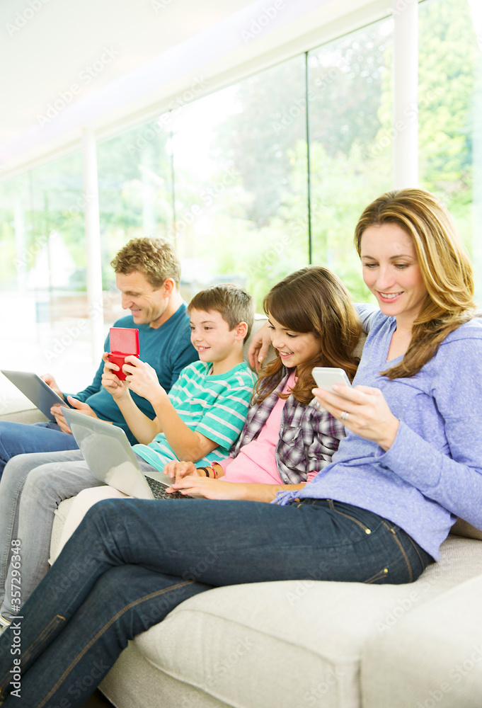 Family using technology on sofa Family using technology on sofa