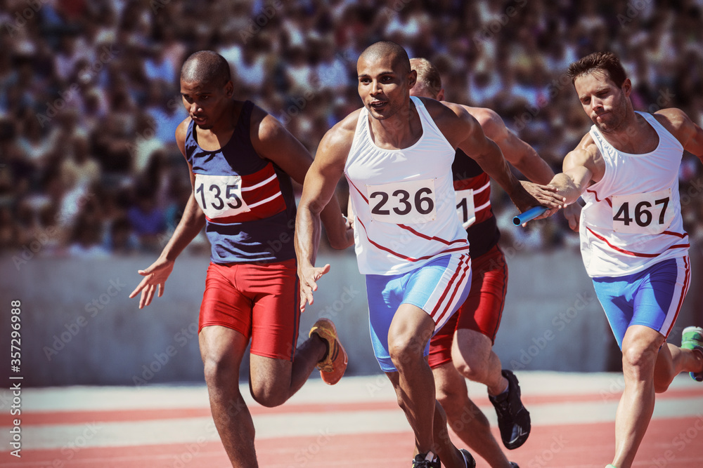 Fototapeta premium Relay runners exchanging batons on track