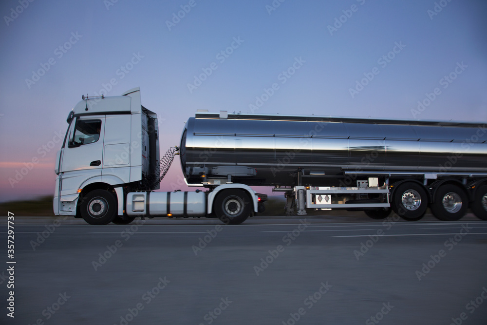 Obraz premium Stainless steel milk tanker on the road at night