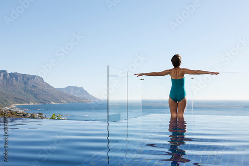 Woman basking in infinity pool overlooking ocean