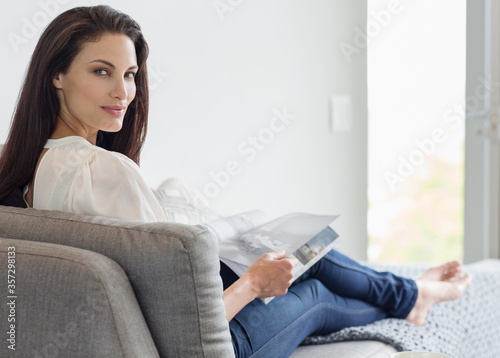 Slika na platnu Portrait of confident woman reading magazine on chaise lounge