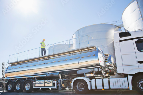 Worker on platform above stainless still milk tanker photo