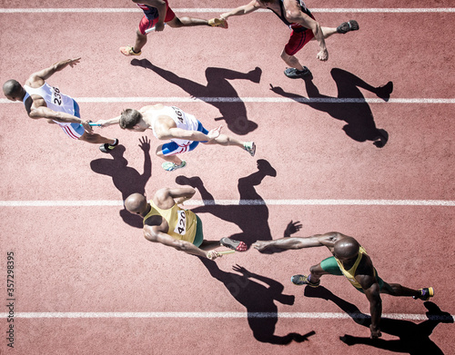 Fototapeta Naklejka Na Ścianę i Meble -  Relay runners handing off batons on track
