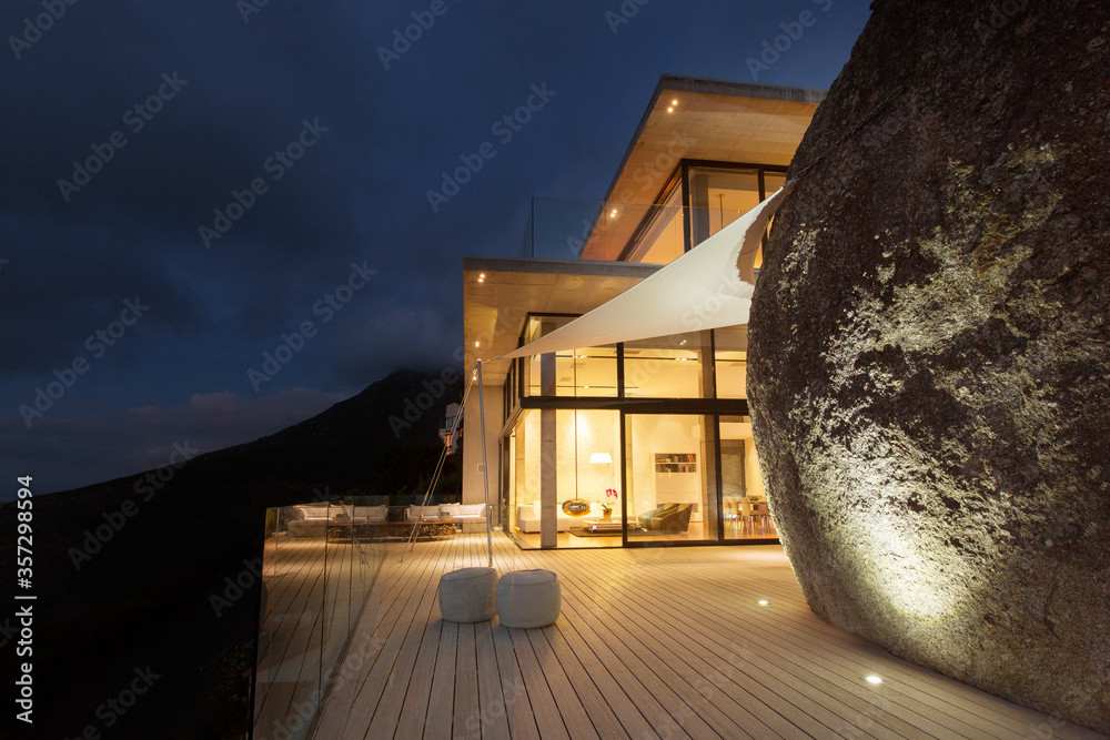 Illuminated modern house with rock feature and balcony Stock Photo ...
