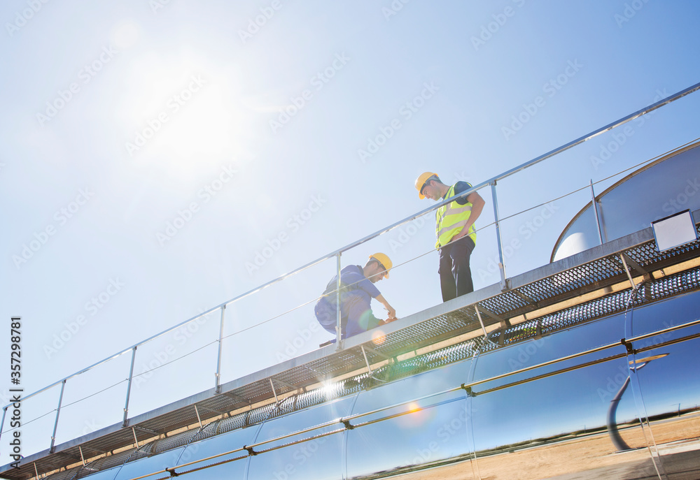 Workers on platform above stainless steel milk tanker