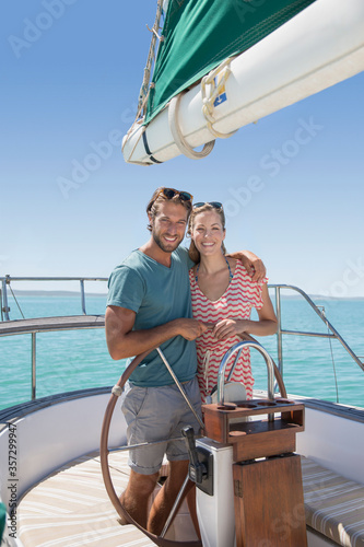 Couple steering sailboat together  © Robert Daly/KOTO