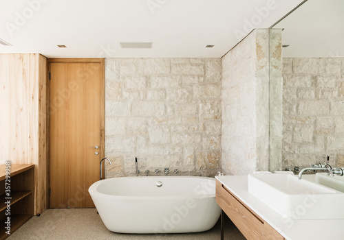 Stone walls behind soaking tub in modern bathroom