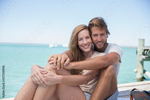 Couple sitting together on edge of wooden dock