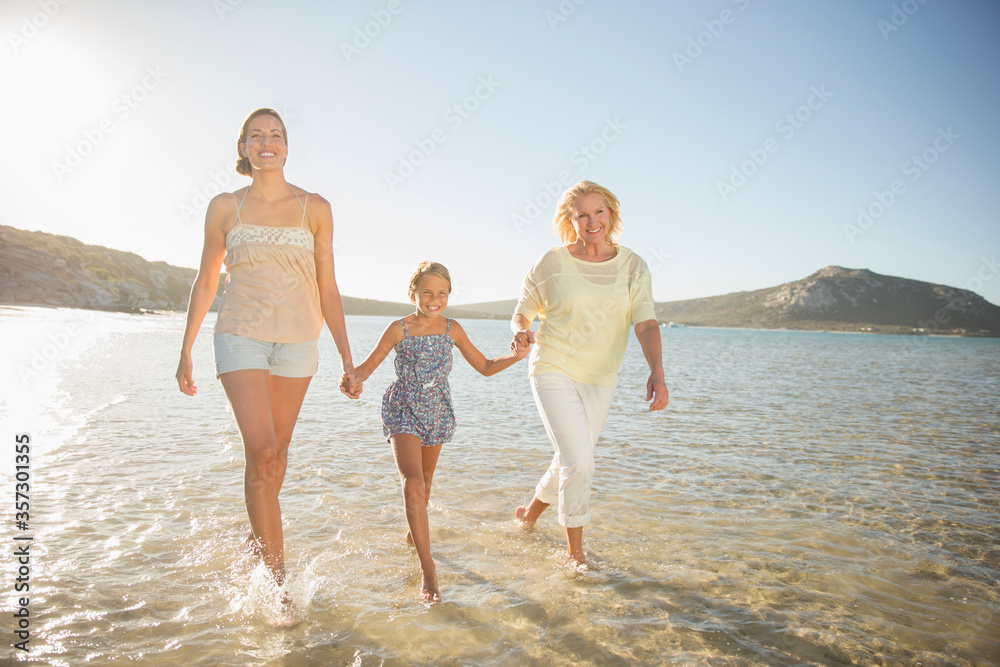 Three generations of women walking in waves Three generations of women walking in waves