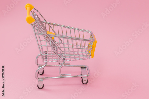 miniature shopping trolley on a pink background.