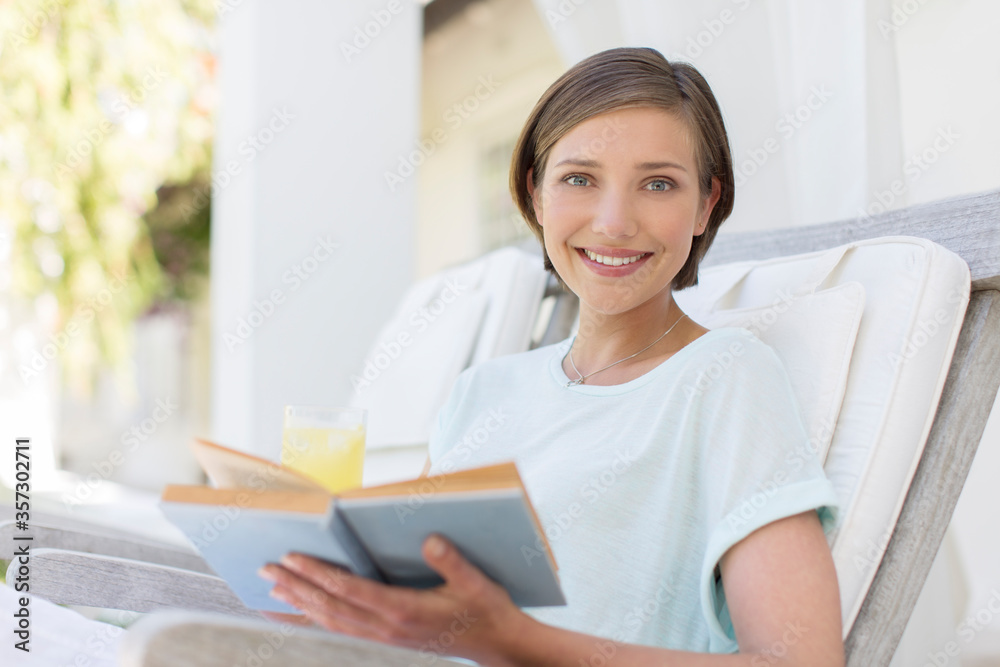 Smiling woman reading book in lawn chair Smiling woman reading book in lawn chair